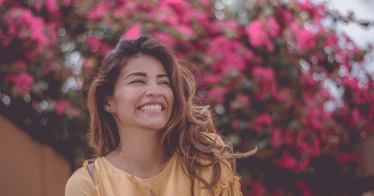 Girl with a perfect smile smiles with flowers in the background